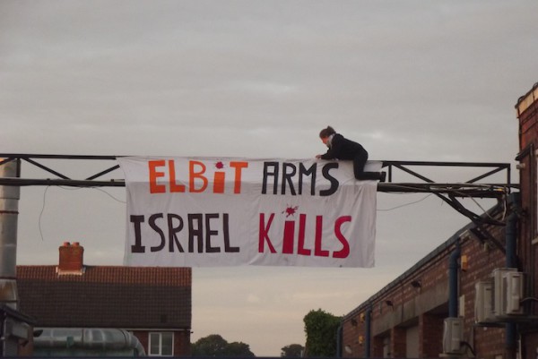Protester-hangs-_Elbit-Arms-Israel-Kills_-at-shutdown-Elbit-factory-in-Birmingham.-The-factory-produces-drone-engines-which-are-exported-to-Israel-and-used-over-Gaza-copy