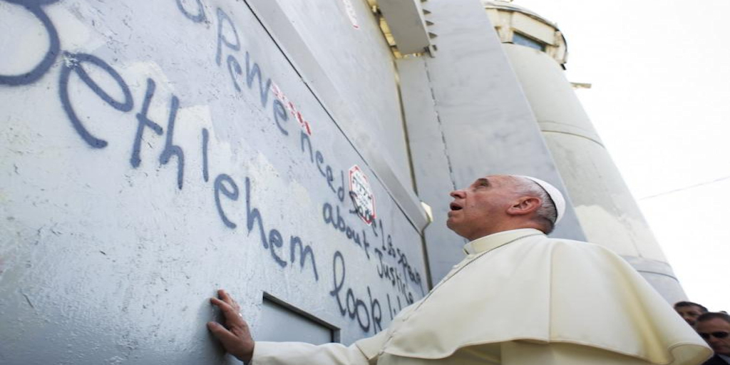 Pope Francis touches Israel's wall on his way to celebrate a mass in the Palestinian West Bank city of Bethlehem May 25, 2014