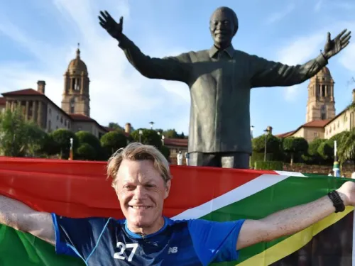 British comedian Eddie Izzard holds a South African flag beneath a statue of former president Nelson Mandela at the government’s Union Buildings in Pretoria, South Africa, Sunday, March 20, 2016. (AP Photo)