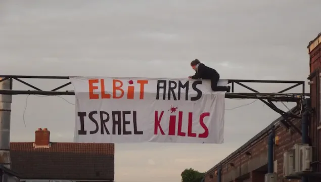 Protester-hangs-_Elbit-Arms-Israel-Kills_-at-shutdown-Elbit-factory-in-Birmingham.-The-factory-produces-drone-engines-which-are-exported-to-Israel-and-used-over-Gaza-copy.jpg