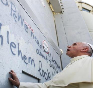 Pope Francis touches Israel's wall on his way to celebrate a mass in the Palestinian West Bank city of Bethlehem May 25, 2014